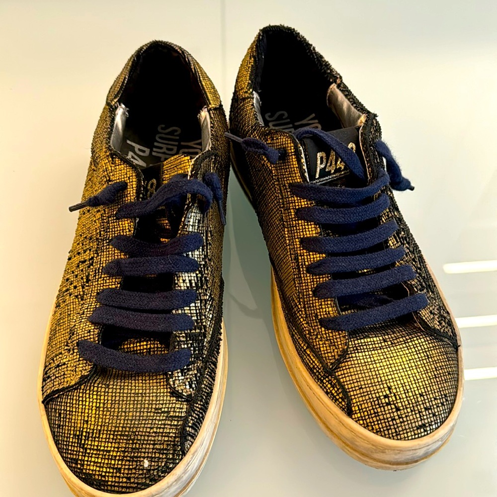 Gold and black low top sneakers.